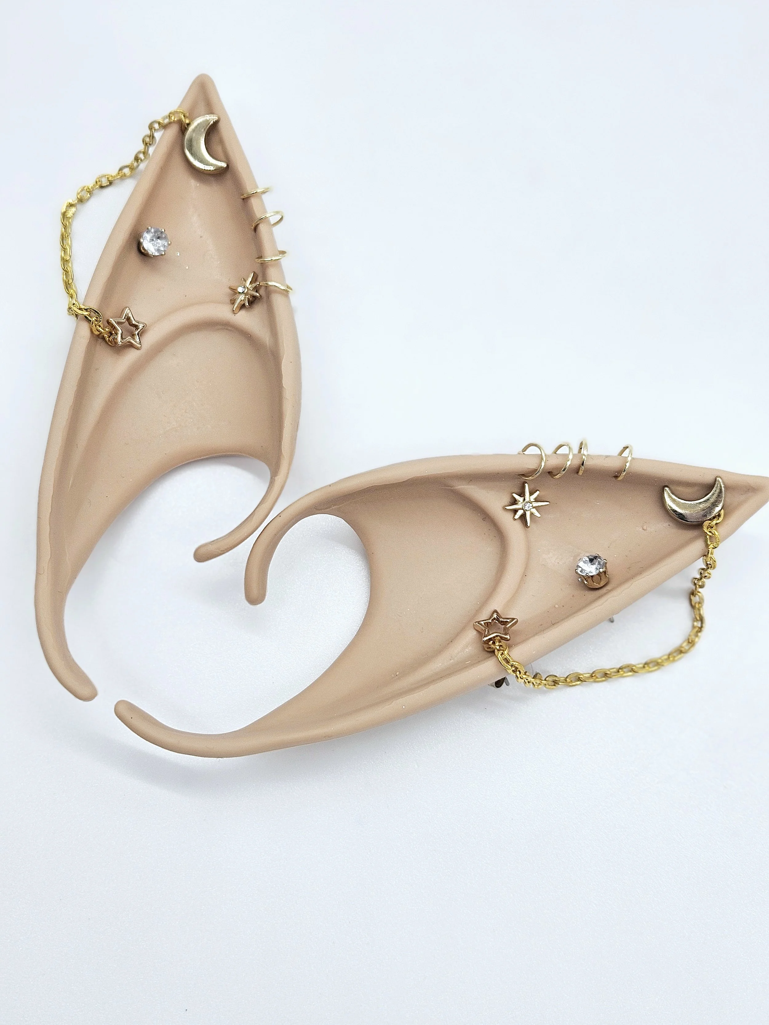 Two beige jewelry display earring holders with gold and silver earrings, some with star, moon, and gemstone designs, on a white background.