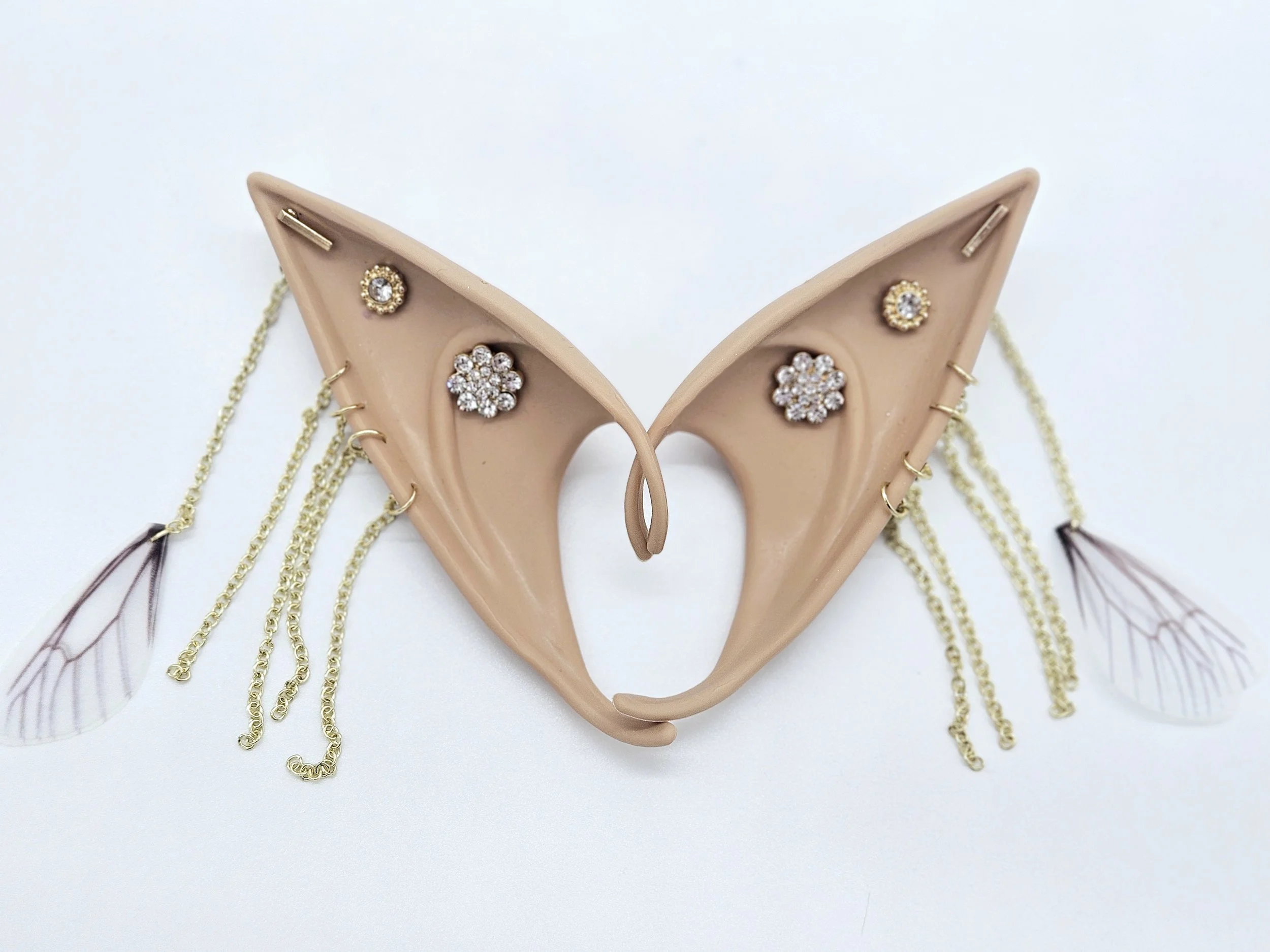 Pink decorative item with gold chains and jewelry, including earrings with floral and gemstone designs, and angel wings with pink feathers.