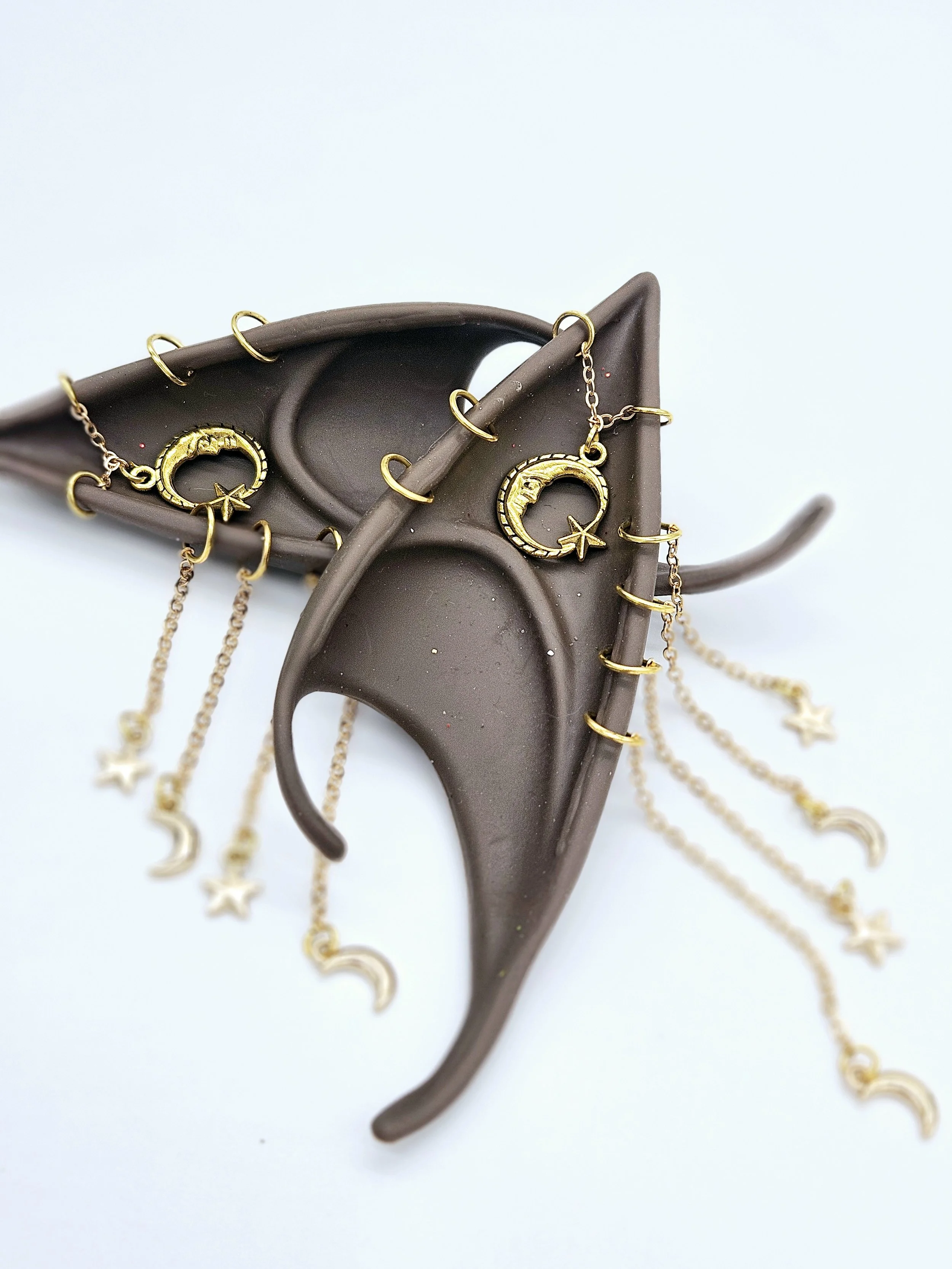A brown hairbrush with gold-colored jewelry, including necklaces and earrings, draped over it.