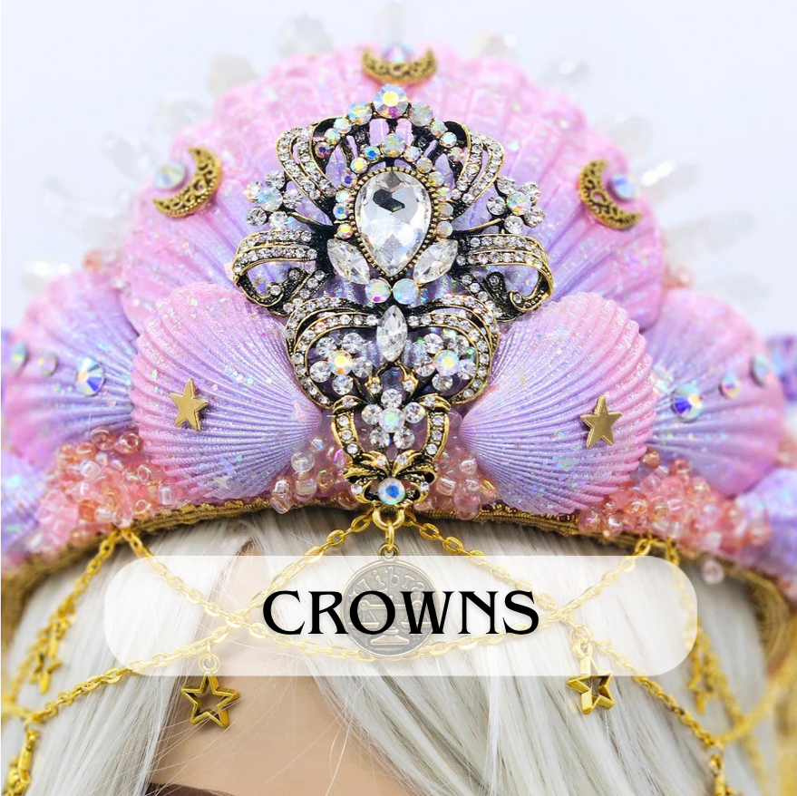 A decorative crown adorned with pink seashells, gold moon and stars, and sparkling rhinestones, worn on a mannequin with white hair.