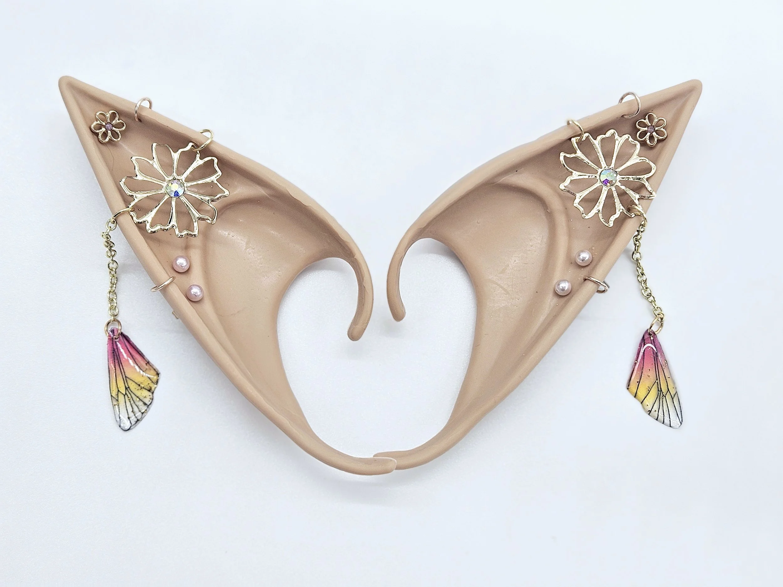 Beige mannequin head with gold floral earrings featuring iridescent rhinestones, pink pearls, and colorful feather dangles.