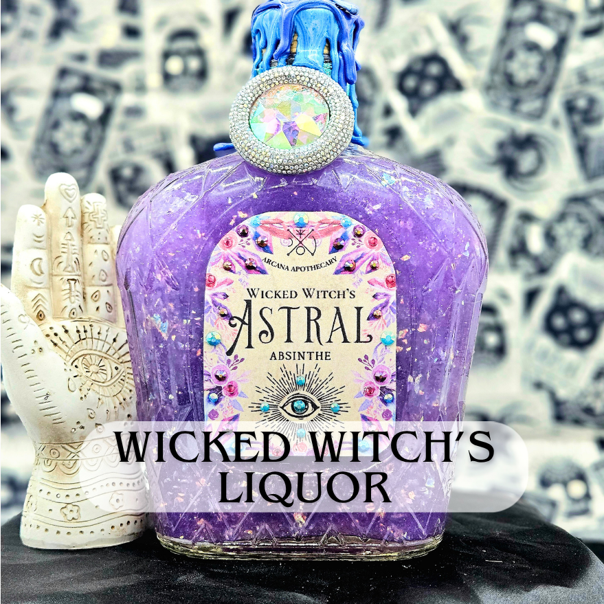 Decorative purple bottle labeled 'Wicked Witch's Astral Absinthe' with a rhinestone-studded cap and blue wax drips on top, placed next to a white hand-shaped ornament with mystical symbols, against a blurry background of black and white dollar bill images.