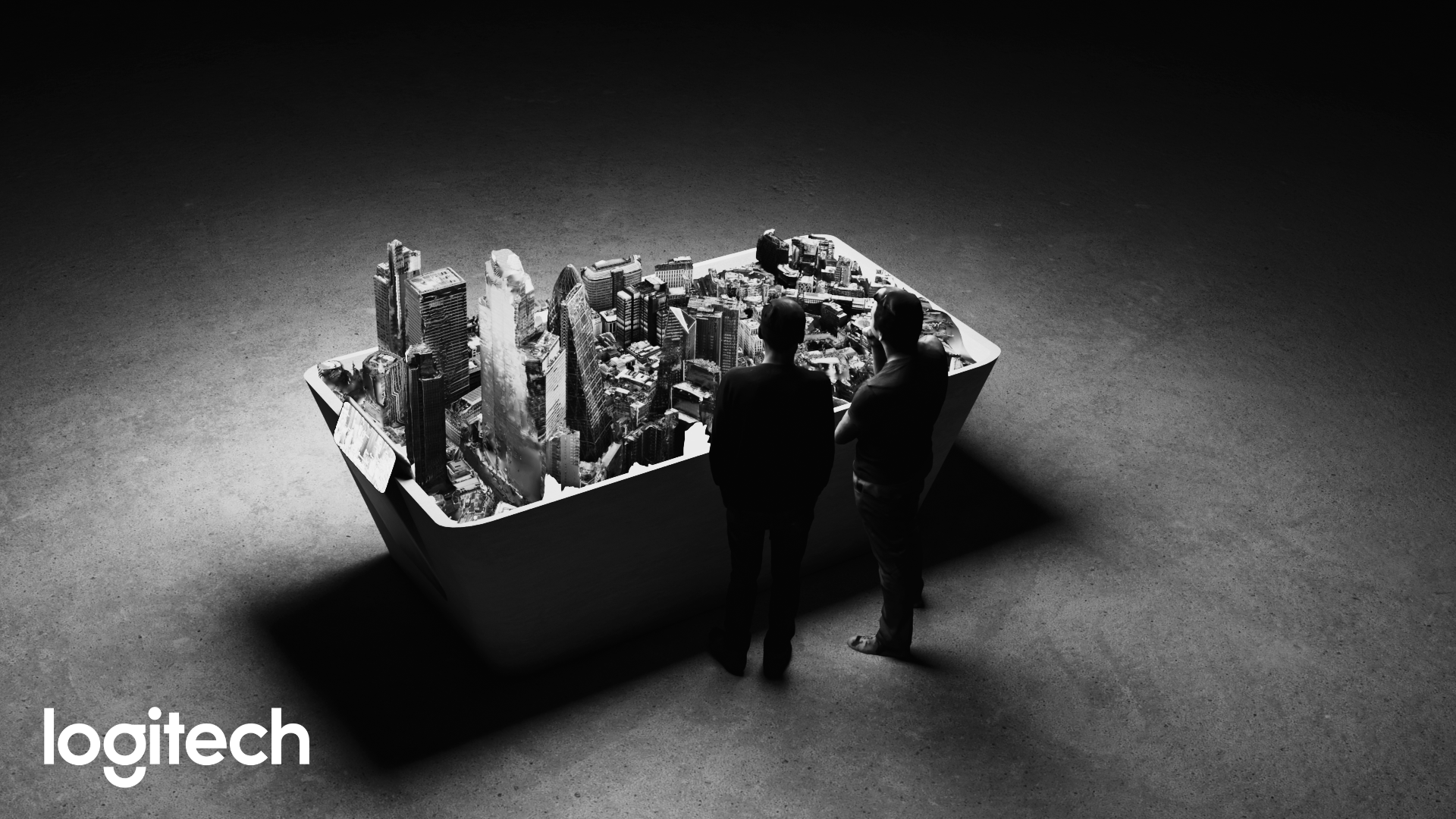 Two men observe a large black-and-white model of a cityscape displayed on a table in a dark room.