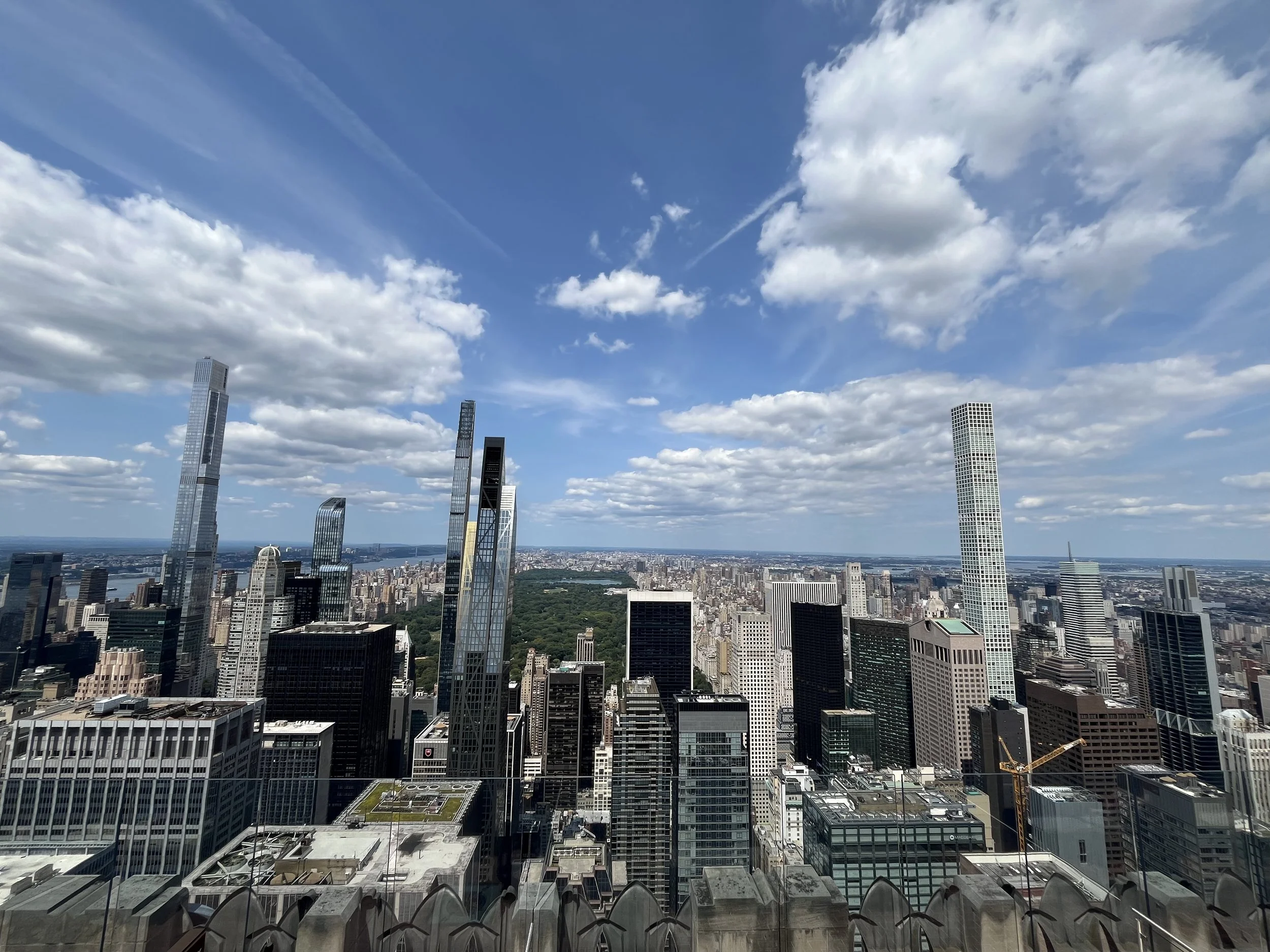 Skyline view of downtown skyscrapers in New York City under partly cloudy sky.