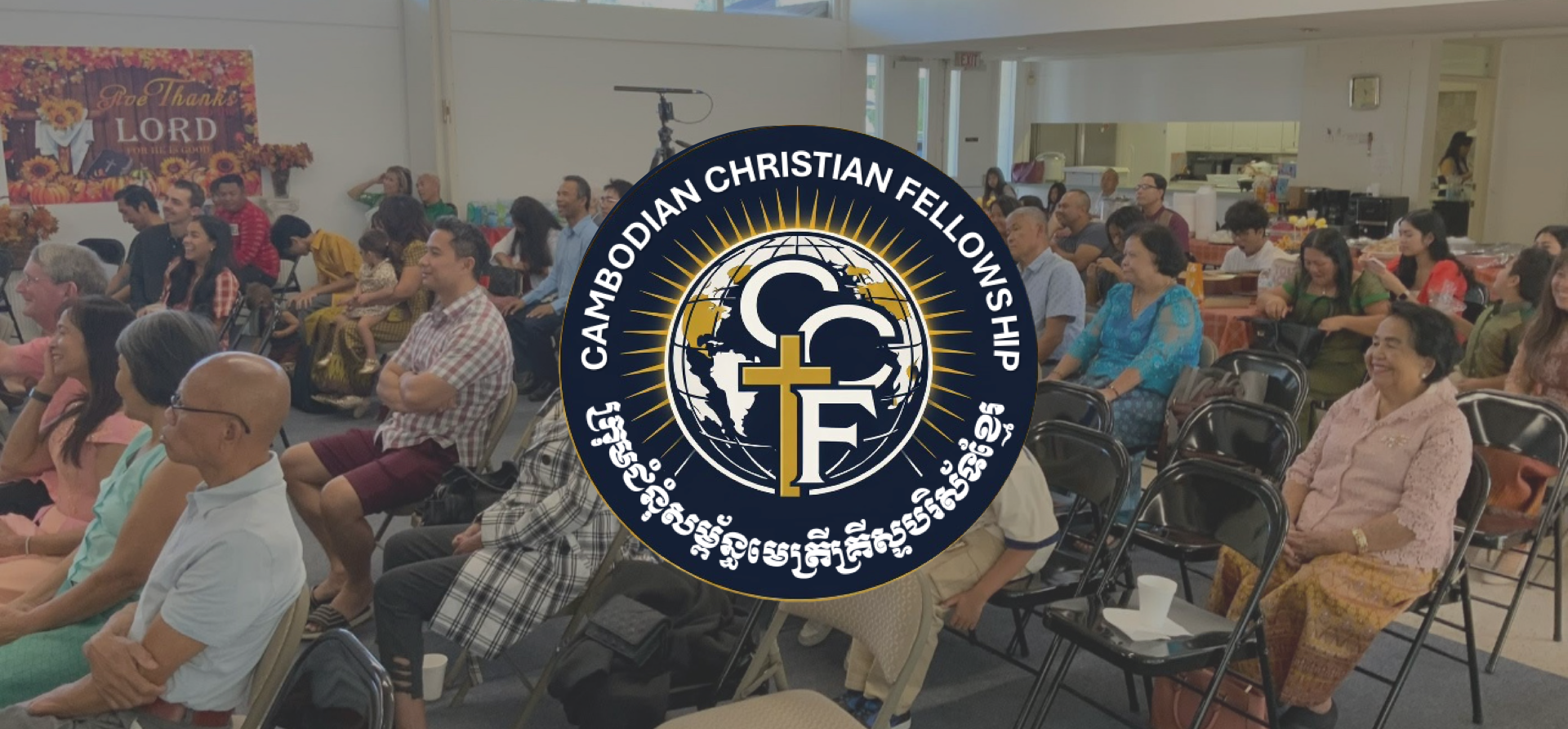 People attending a Christian fellowship event seated in a room with chairs, some smiling and listening, with a large Cambodia Christian Fellowship logo overlayed in the center.