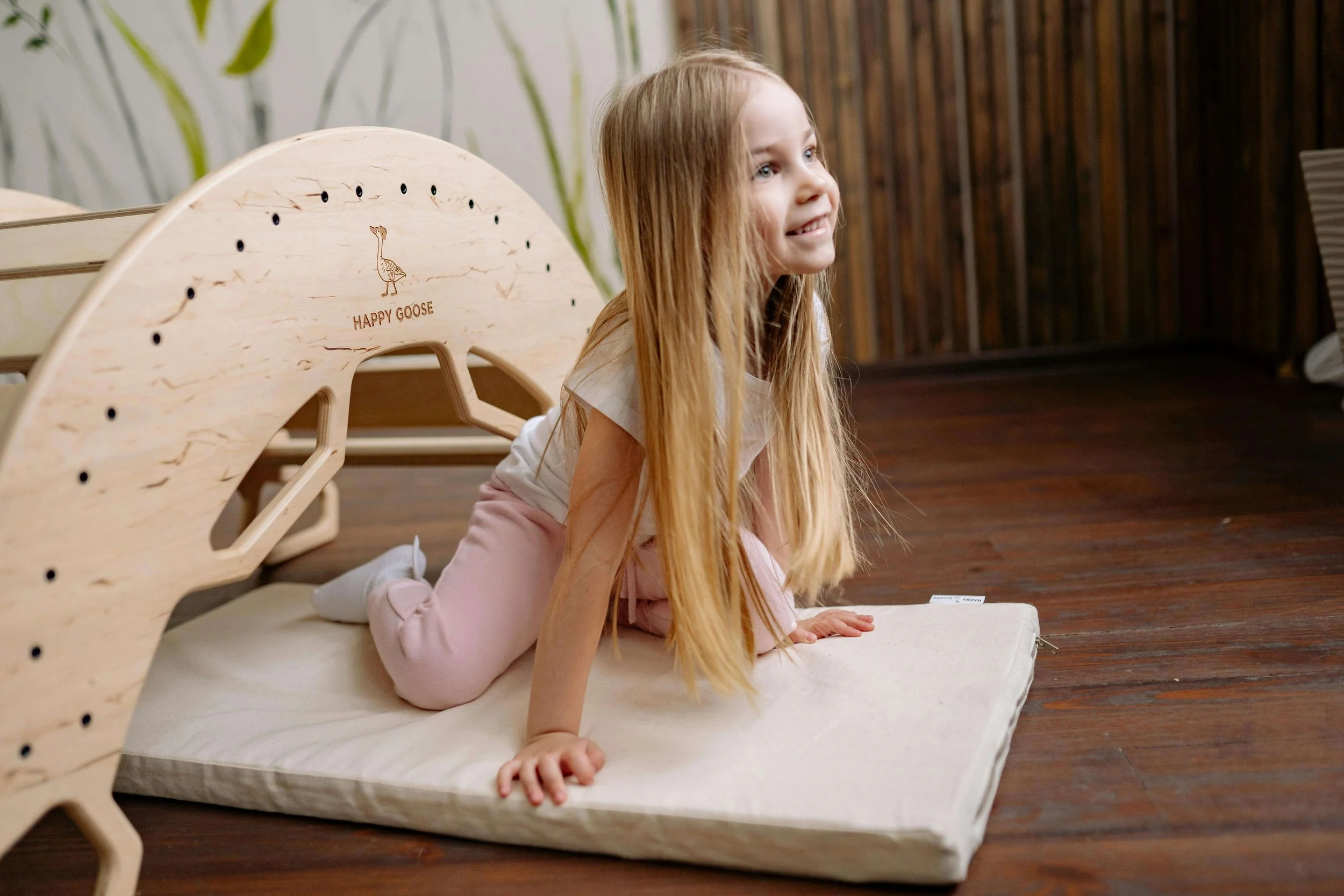 Young girl with long blonde hair sitting on a mat
