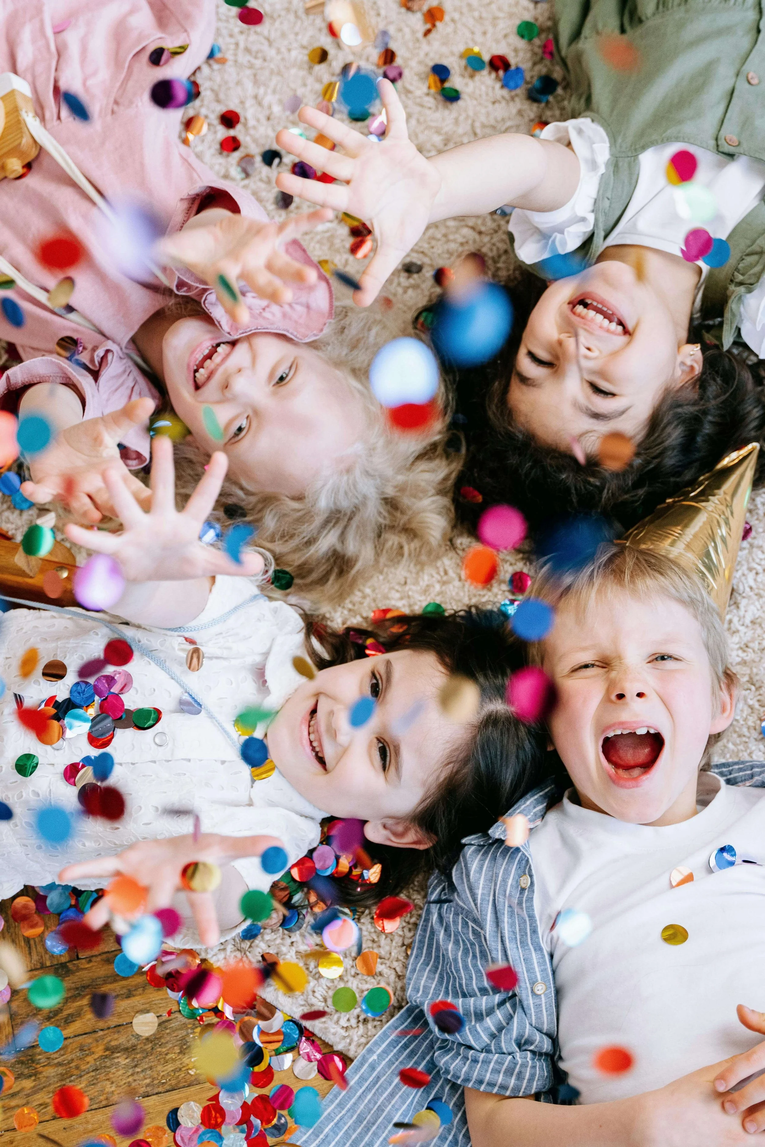Children lying on the floor throwing confetti