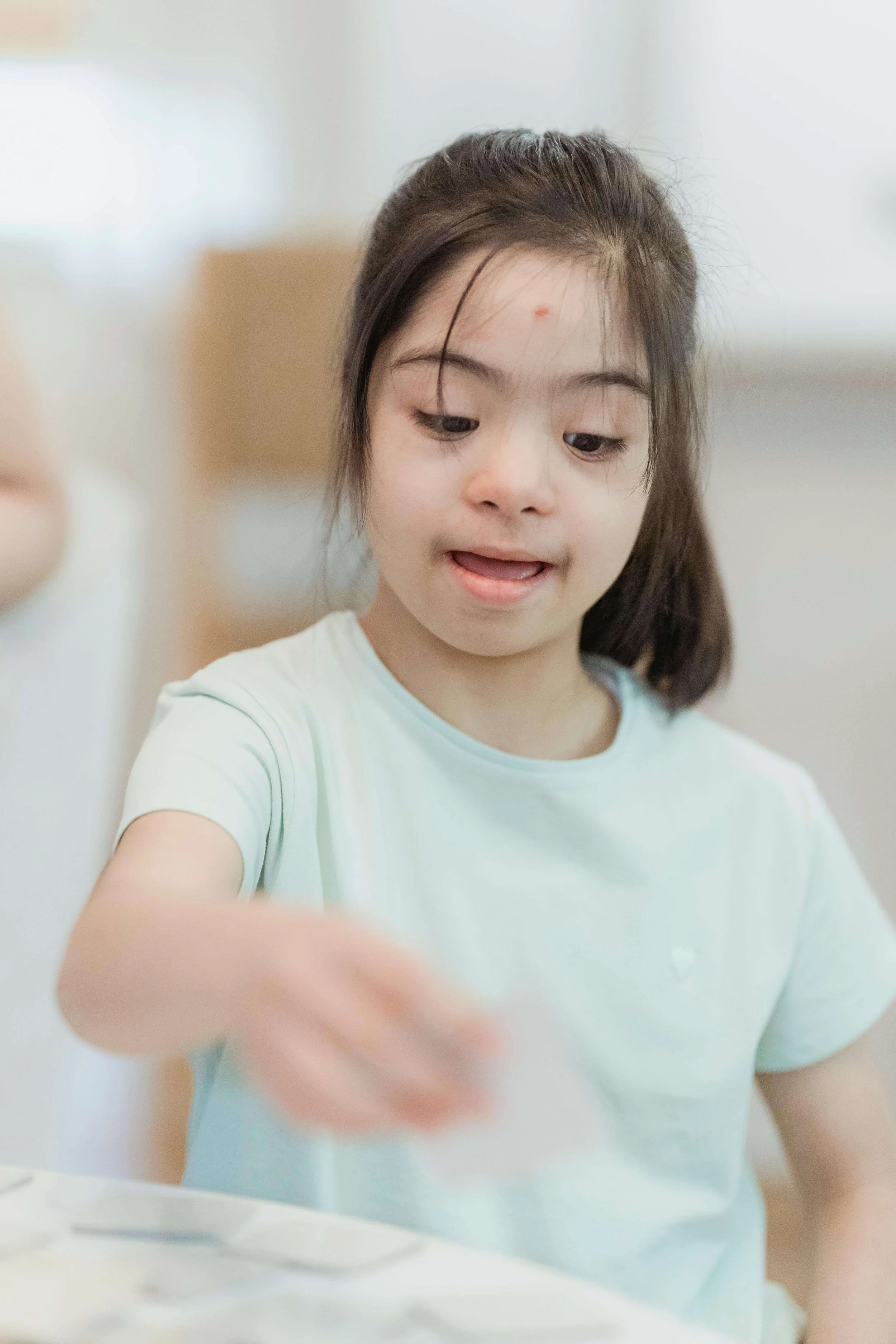 Young girl in blue shirt playing at a table