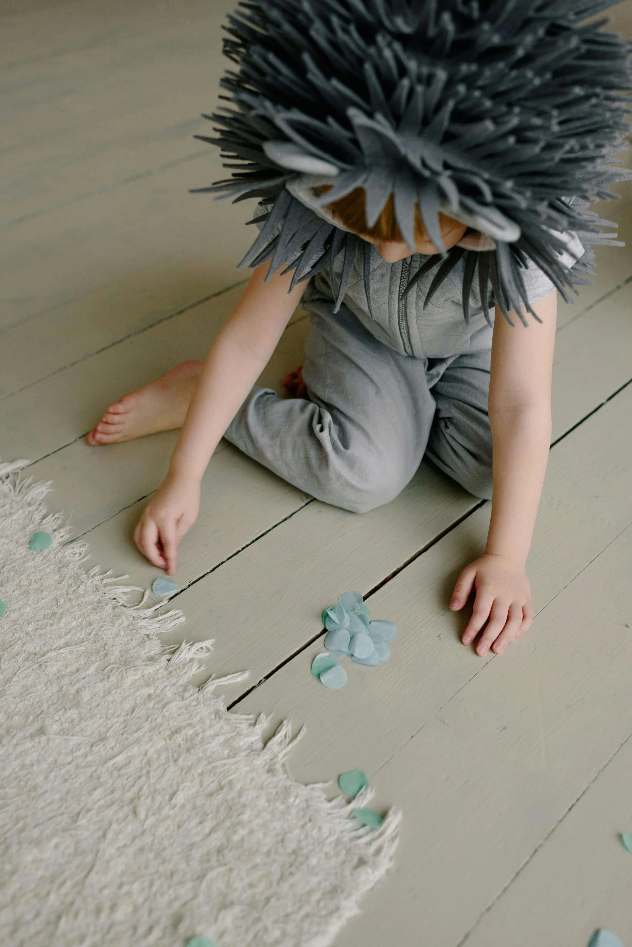 Young boy in a grey costume sitting on the floor