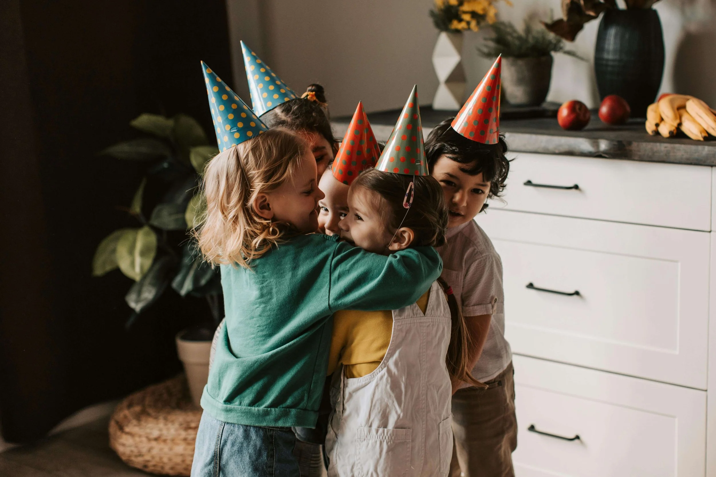 Children in birthday party hats hugging