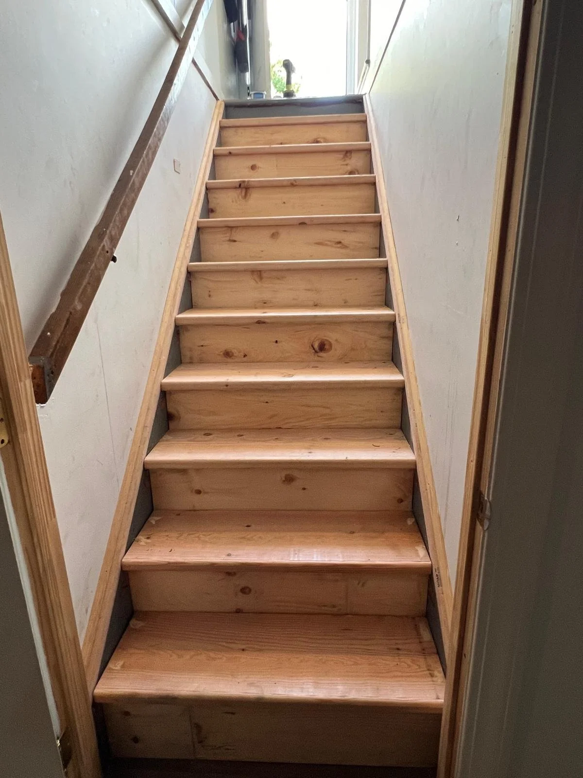Wooden staircase under construction, with steps installed but no railing.
