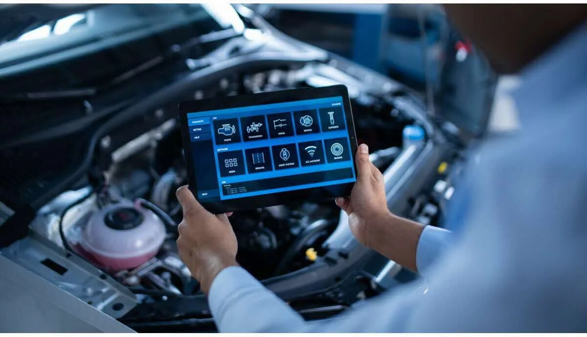 Personne utilisant une tablette pour contrôler un véhicule électrique en réparant ou en configurant ses paramètres, sous le capot d'une voiture