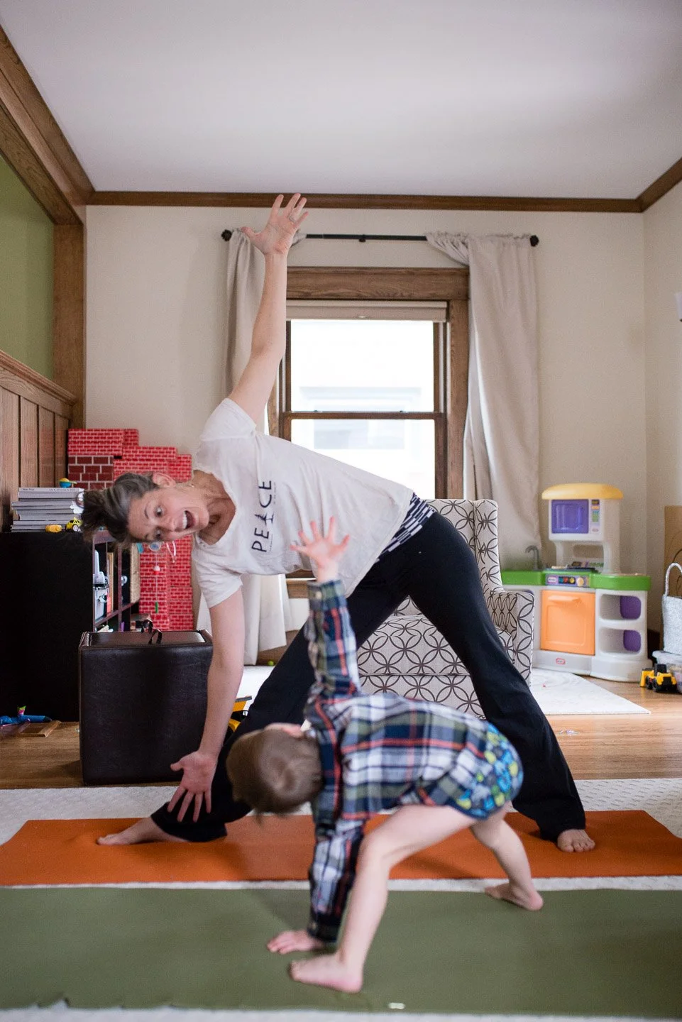 Woman and young boy practicing yoga together in a living room.