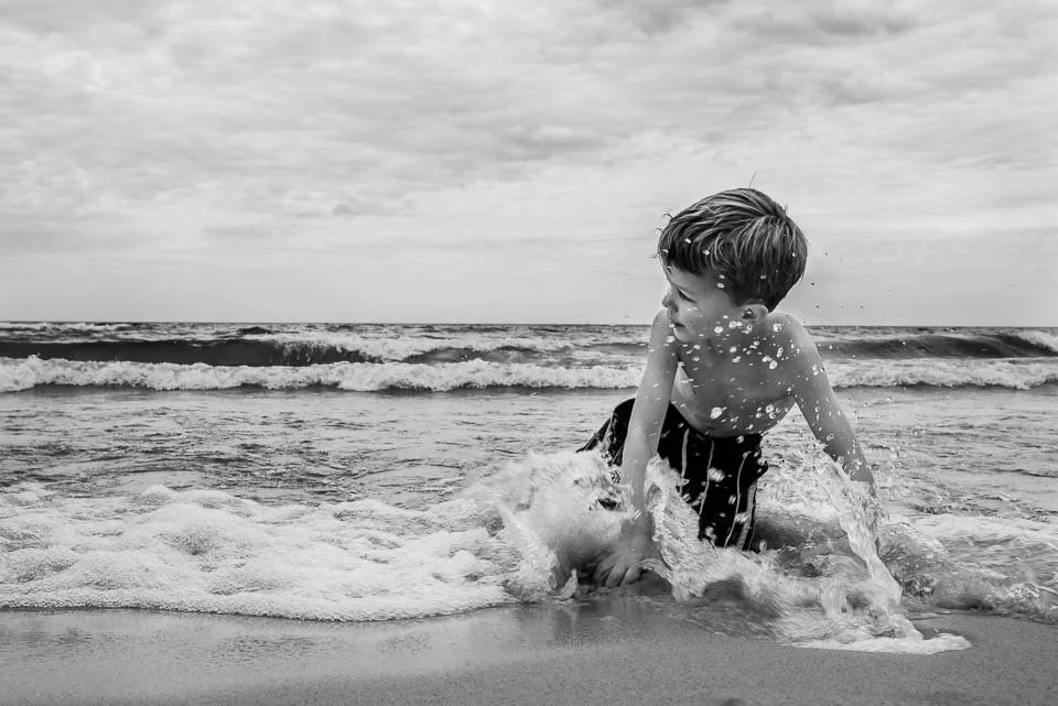 A boy playing and splashing in the ocean waves at the beach.