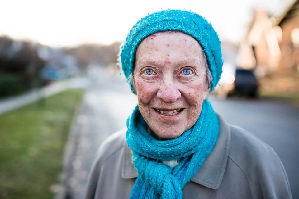 [40/100] Leona - I was headed back to my car at Wilcox Park and saw Leona crossing the street. The vibrant matching blue of her scarf, hat and eyes was striking. I said hello, introduced myself, and commented on her beautiful scarf and hat. She menti