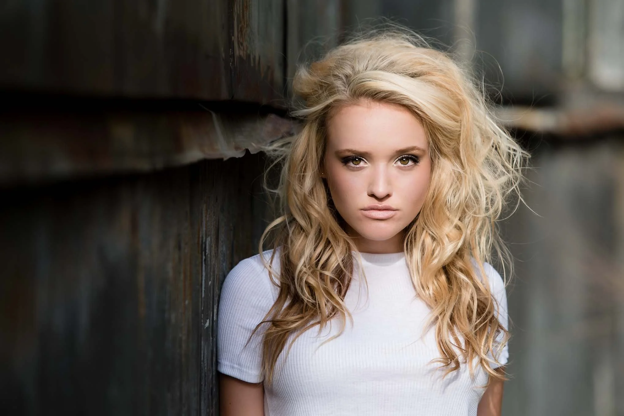 Grand Rapids senior portrait with industrial urban background — senior in white top against rusting sheet metal.