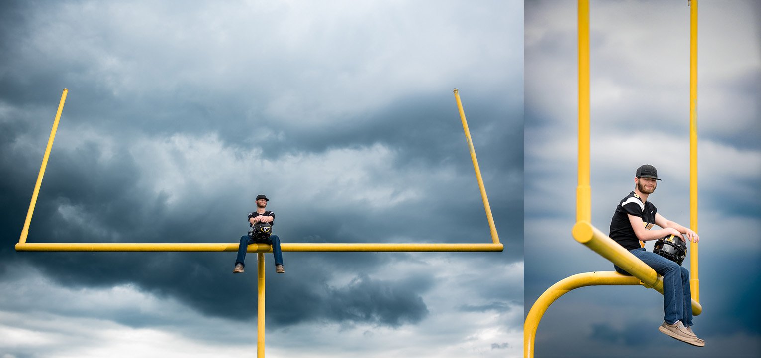 Senior sitting on football goal posts under a stormy sky at Tri County High School