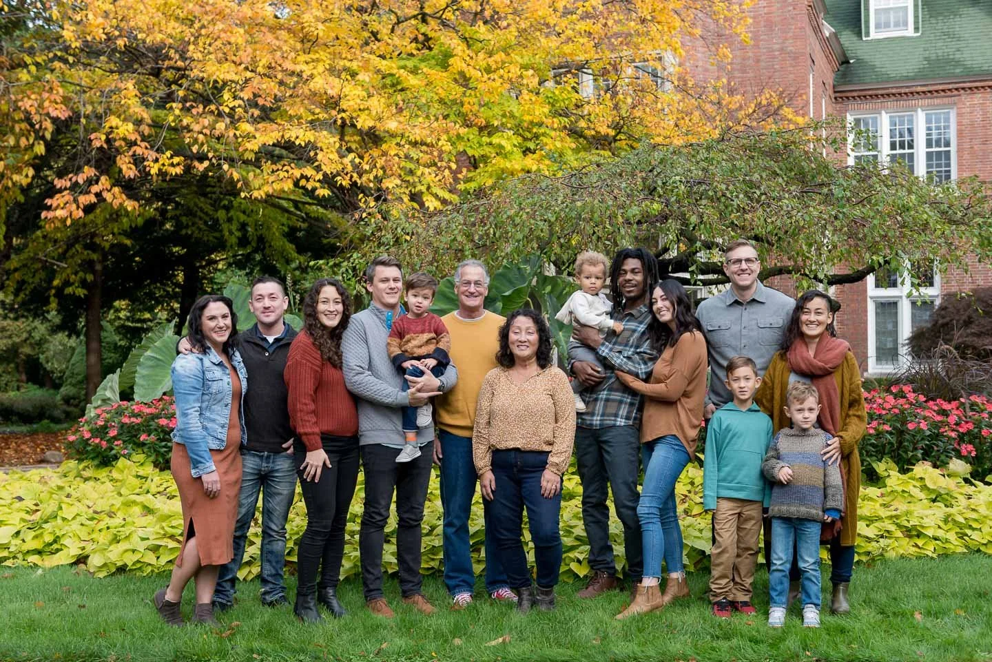 Family group photo outdoors in a garden with fall foliage.