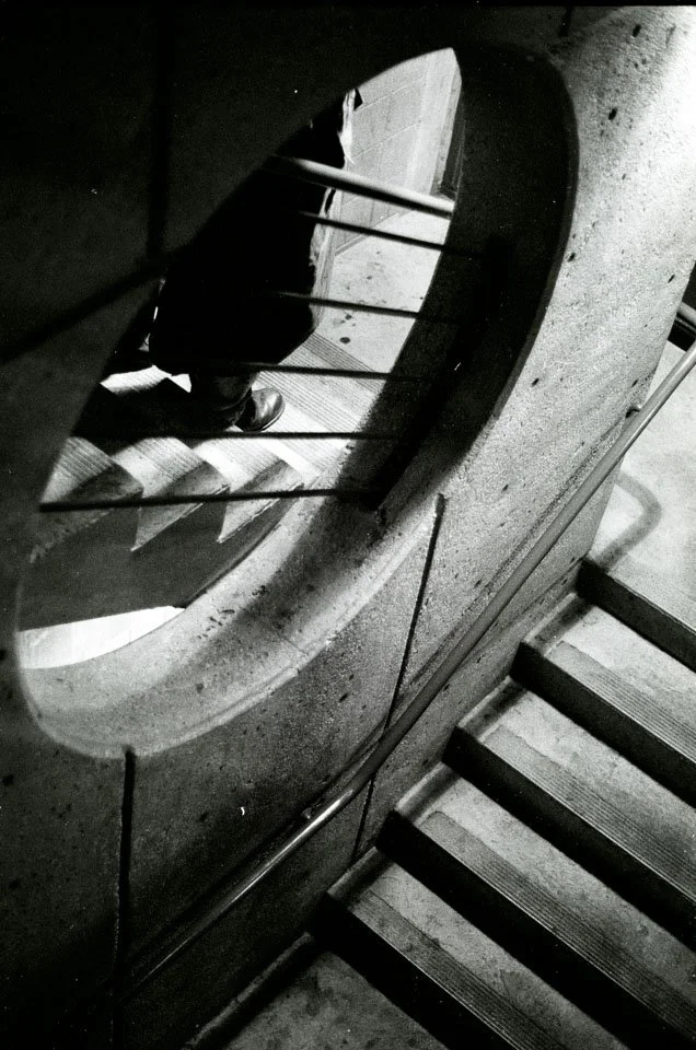 View of a spiral staircase from above, showing the stairs and railing, with a person's foot visible.
