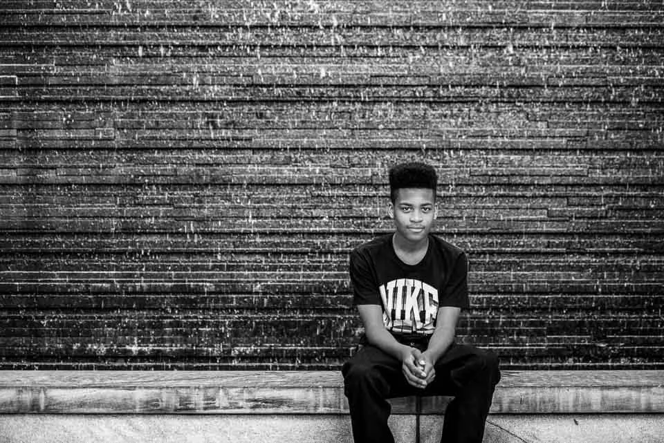 [37/100] Xayvion - I was downtown scouting locations this week, turned a corner, and saw Xayvion sitting on this wall. The lines and tones jumped out at me and I asked him if he would mind if I took a few portraits. Not at all, though his girlfriend 
