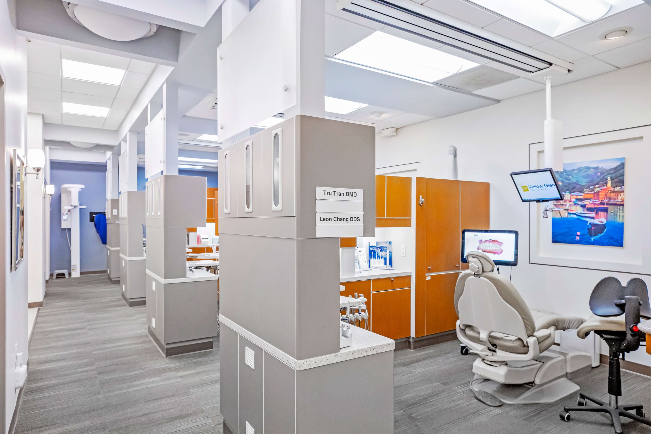 A modern, clean dental office with comfortable dental chairs, many computer monitors, and advanced technology equipment, in a well lit office.
