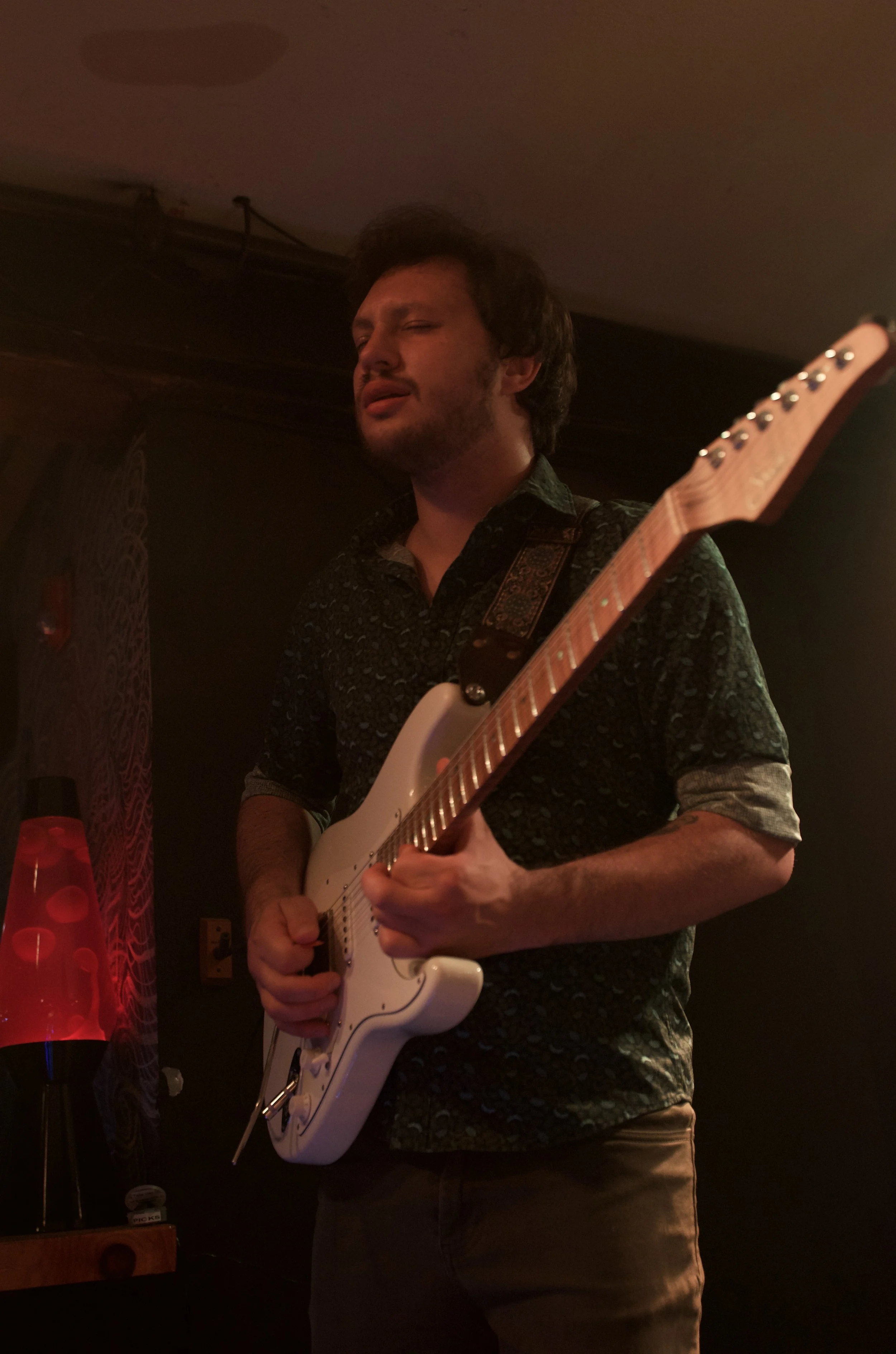 A man playing an electric guitar in a dimly lit room.