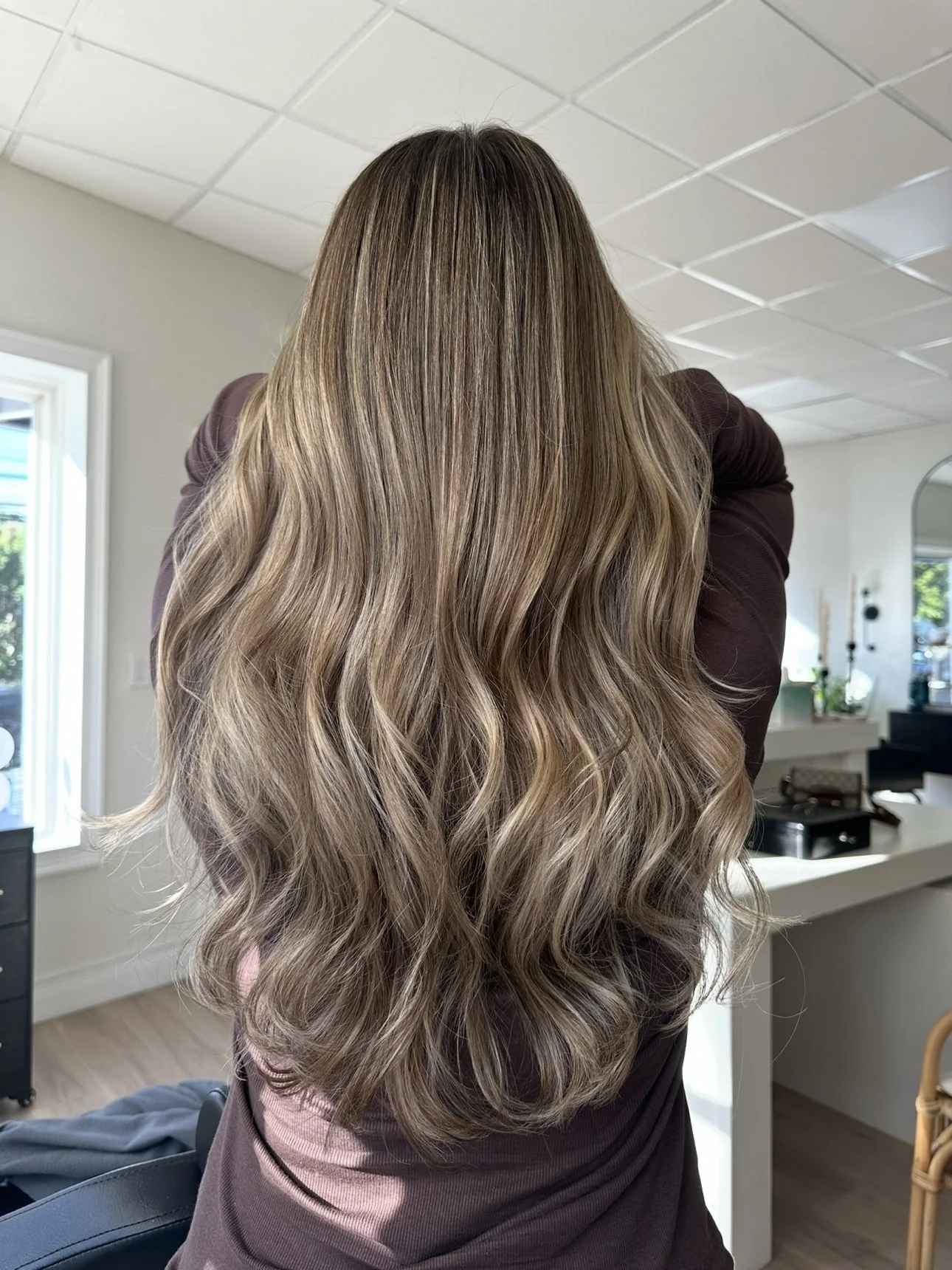 Long, wavy blonde hair created with low-maintenance color techniques by Beauty By Kell Cart.