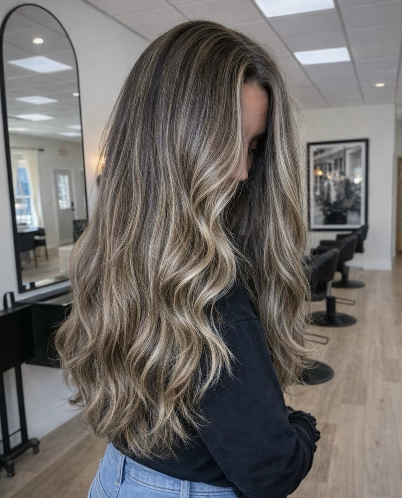 Woman with long, wavy blonde hair in a salon or hair studio.