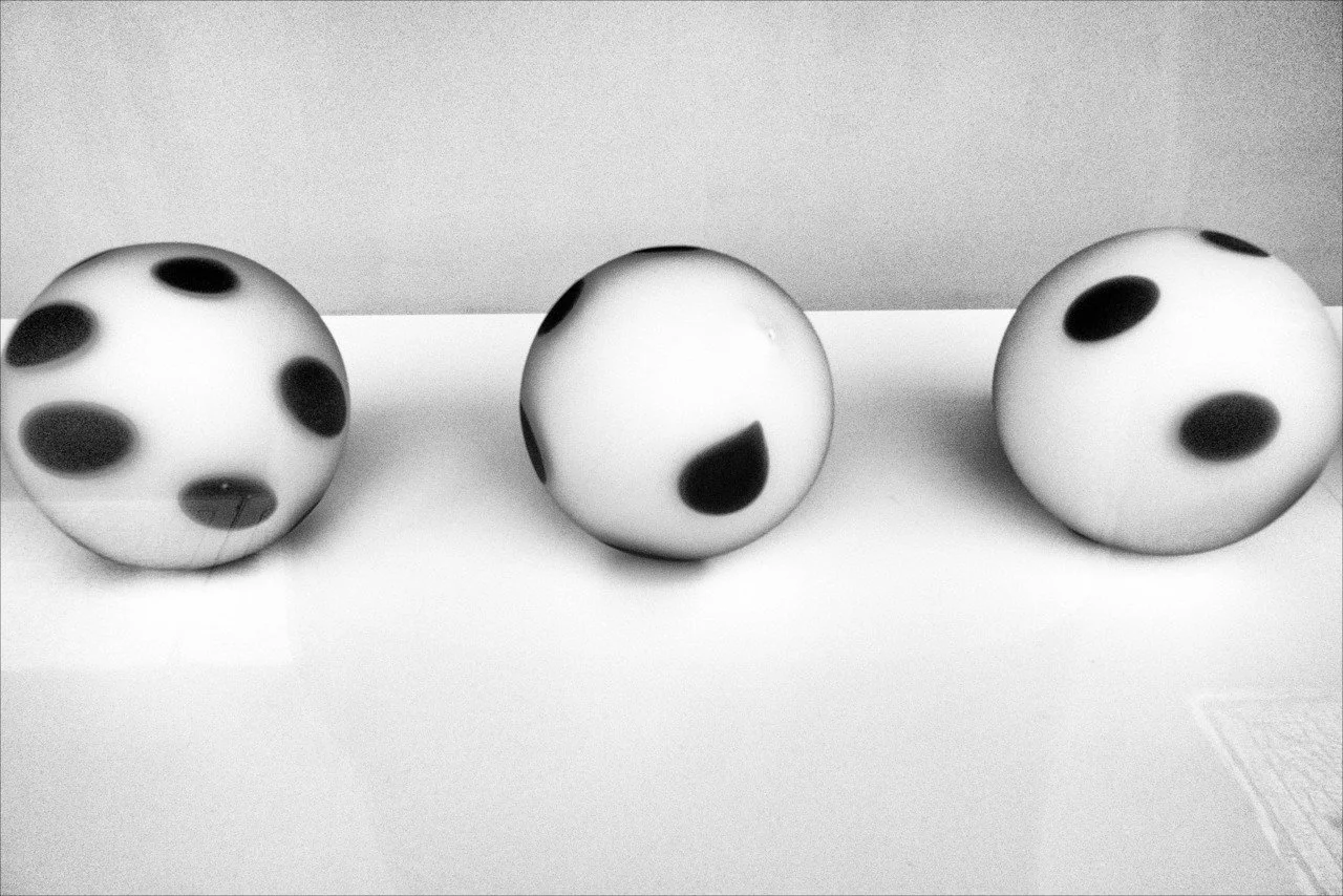 Three white spherical objects with black spots on a flat surface.
