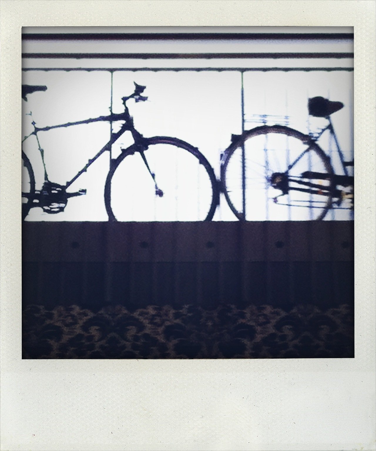 Silhouette of two bicycles mounted on a white wall with horizontal black stripes.