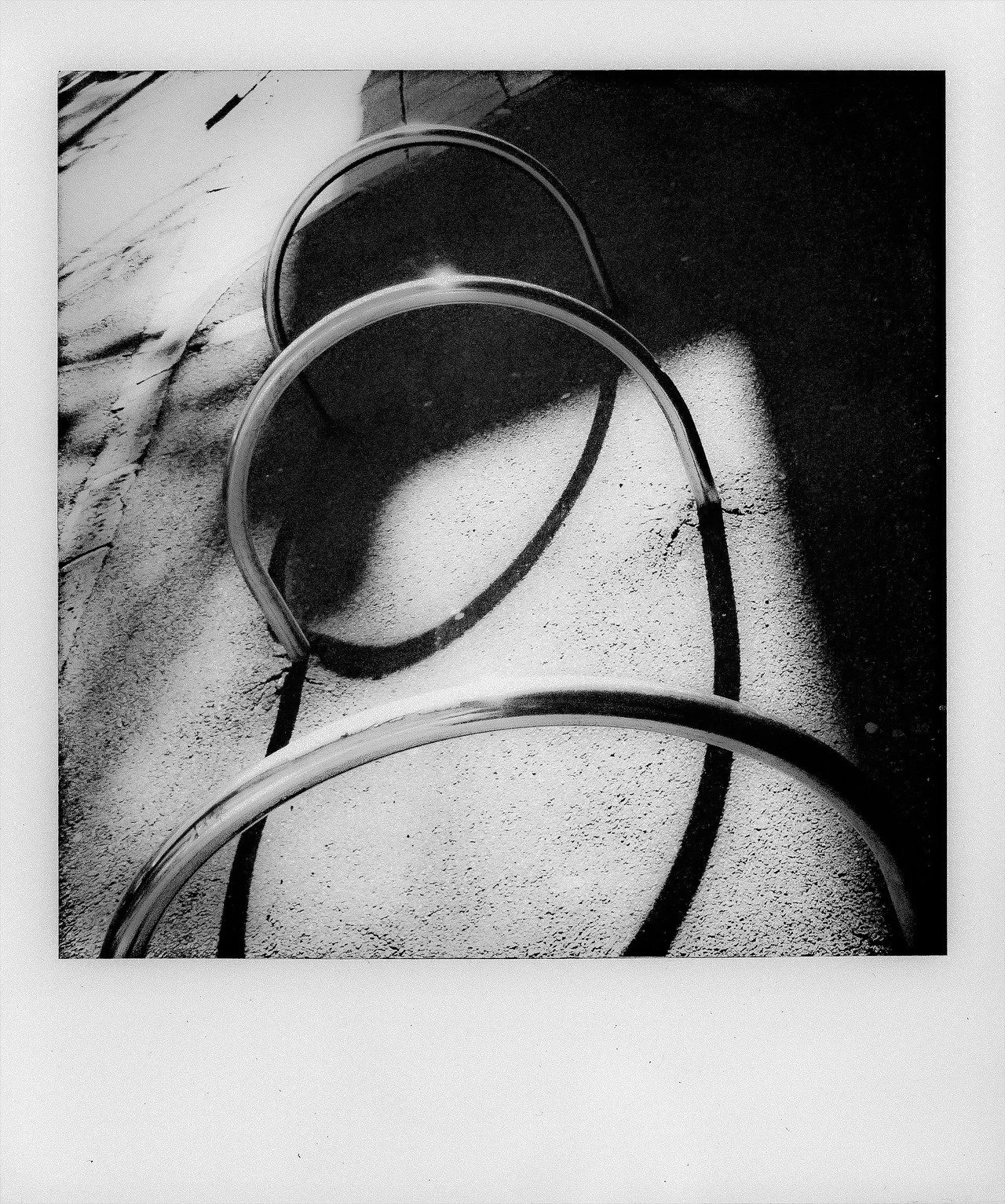 Black and white photo of three hat hoops on a textured surface with a wall in the background.
