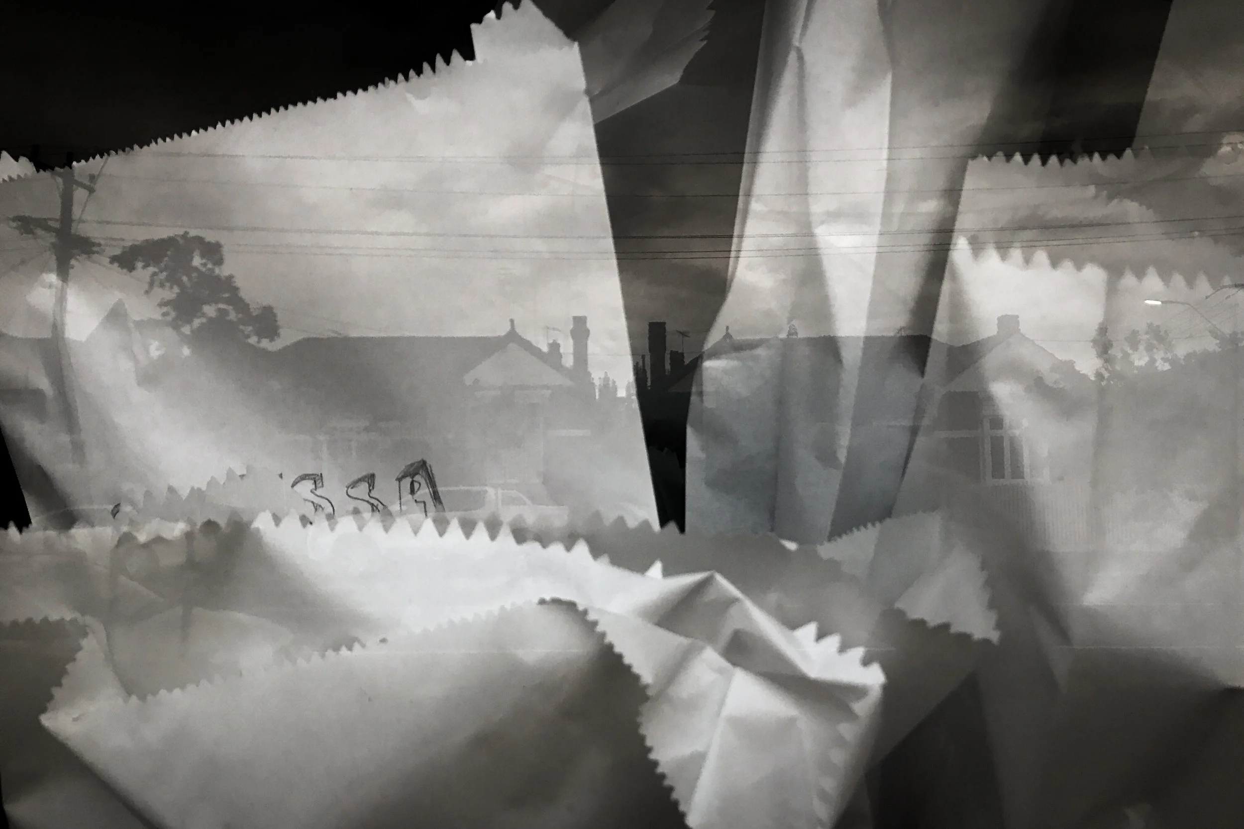 A layered black-and-white photo showing a suburban neighborhood with houses, trees, and power lines, overlaid with crumpled paper edges.