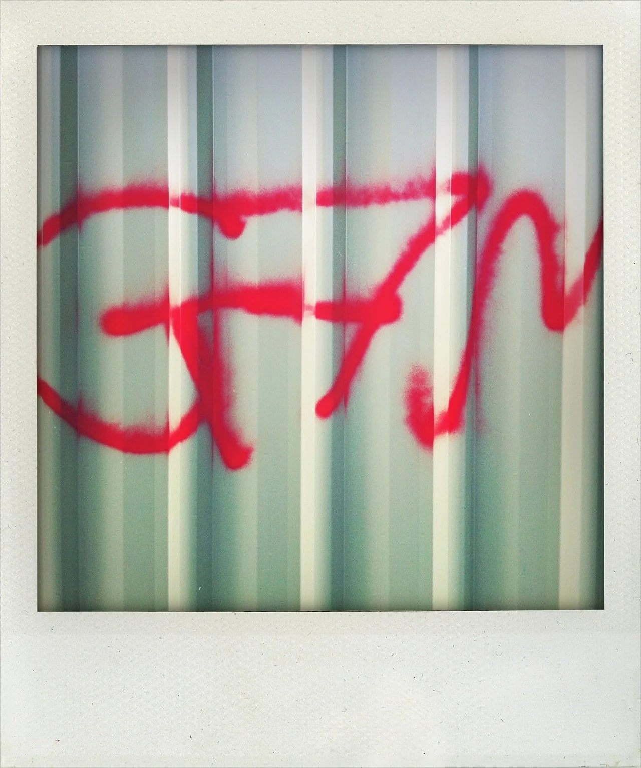 Red spray-painted word on a metal surface with vertical ridges.