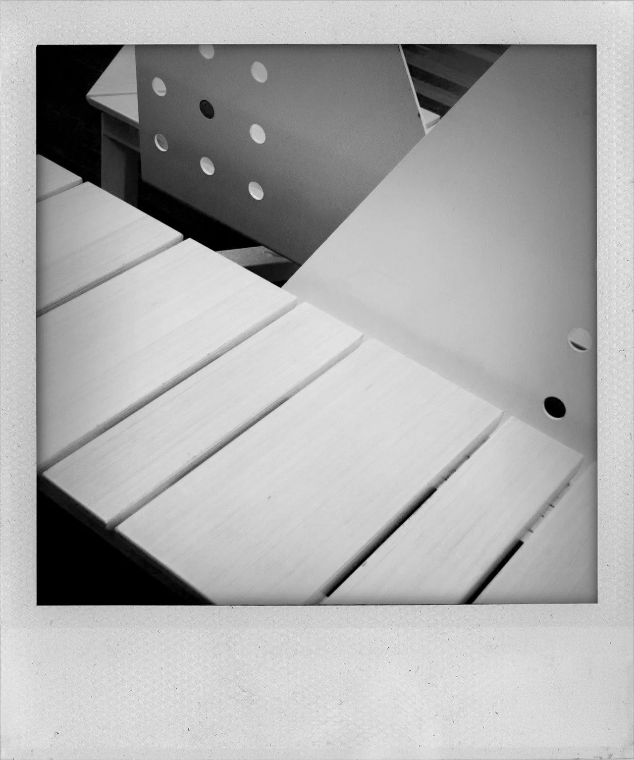 Black and white photo of furniture with a slatted surface and rounded metal supports, creating a minimalist aesthetic.