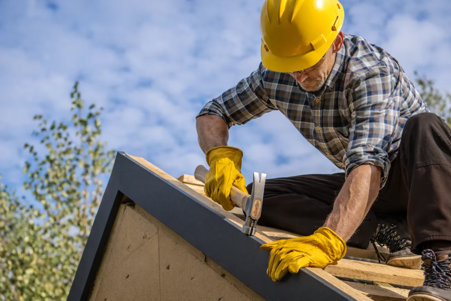 Roofer working on roof hardhat and hammer