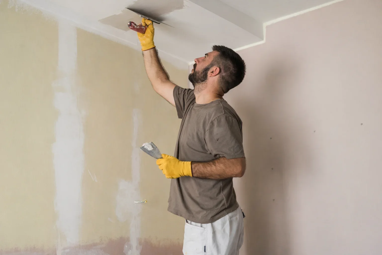 Contractor working on joint compound on ceiling