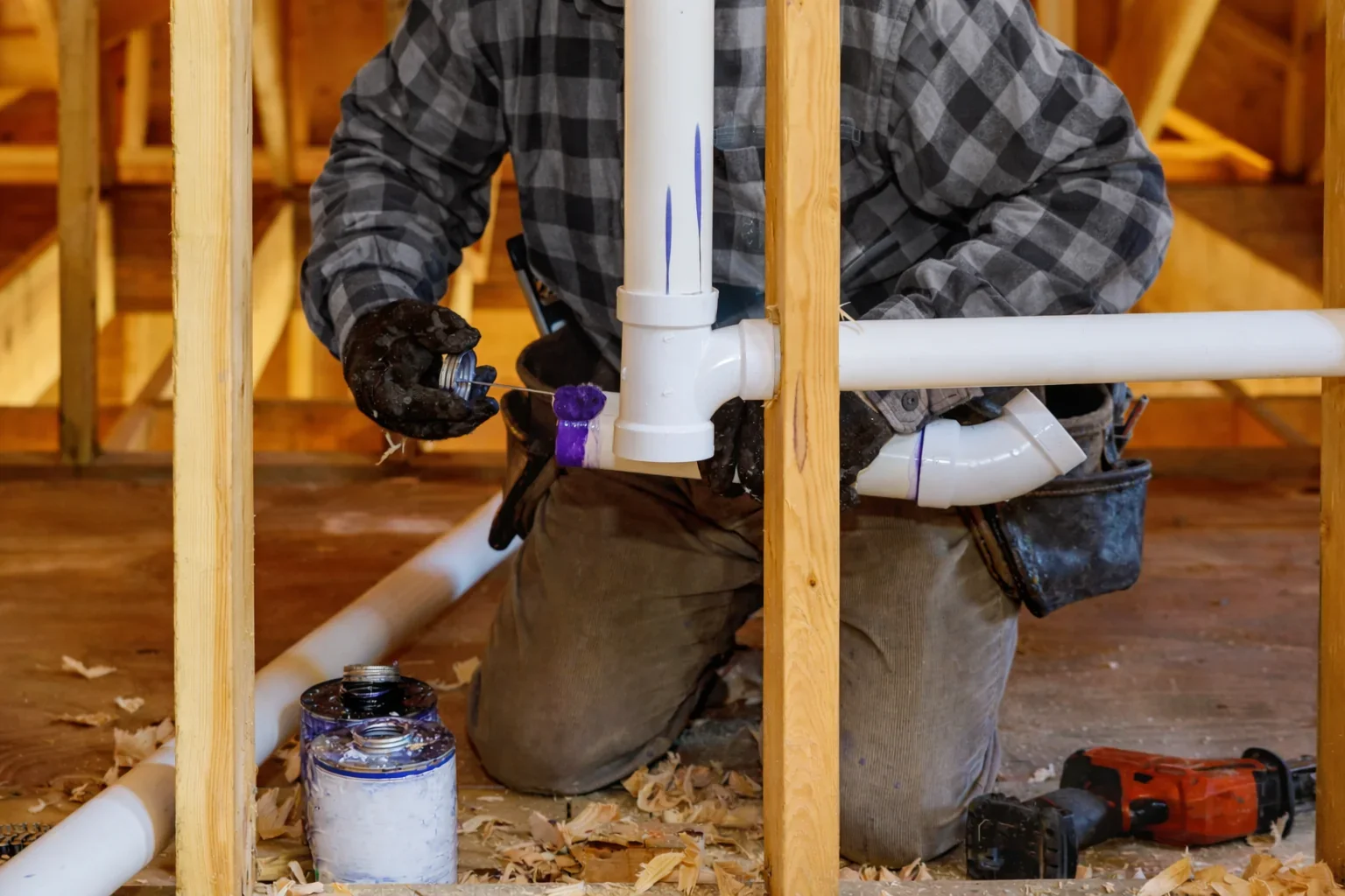 Plumber applying pvc adhesive for plumbing in new construction