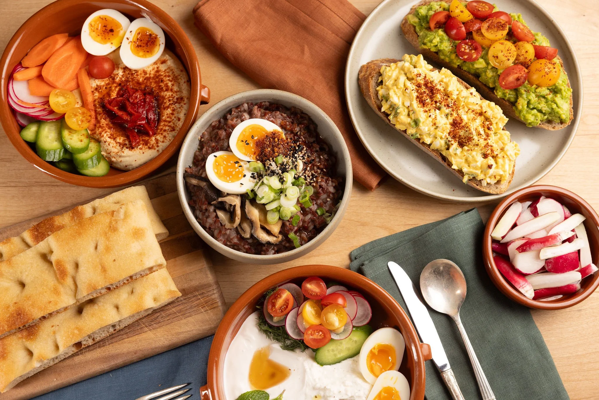 Pictured from left to right, back to front: Pepper Trio Hummus, Savory Porridge, Deviled Egg Toast, Avocado Toast and Persian Breakfast Bowl