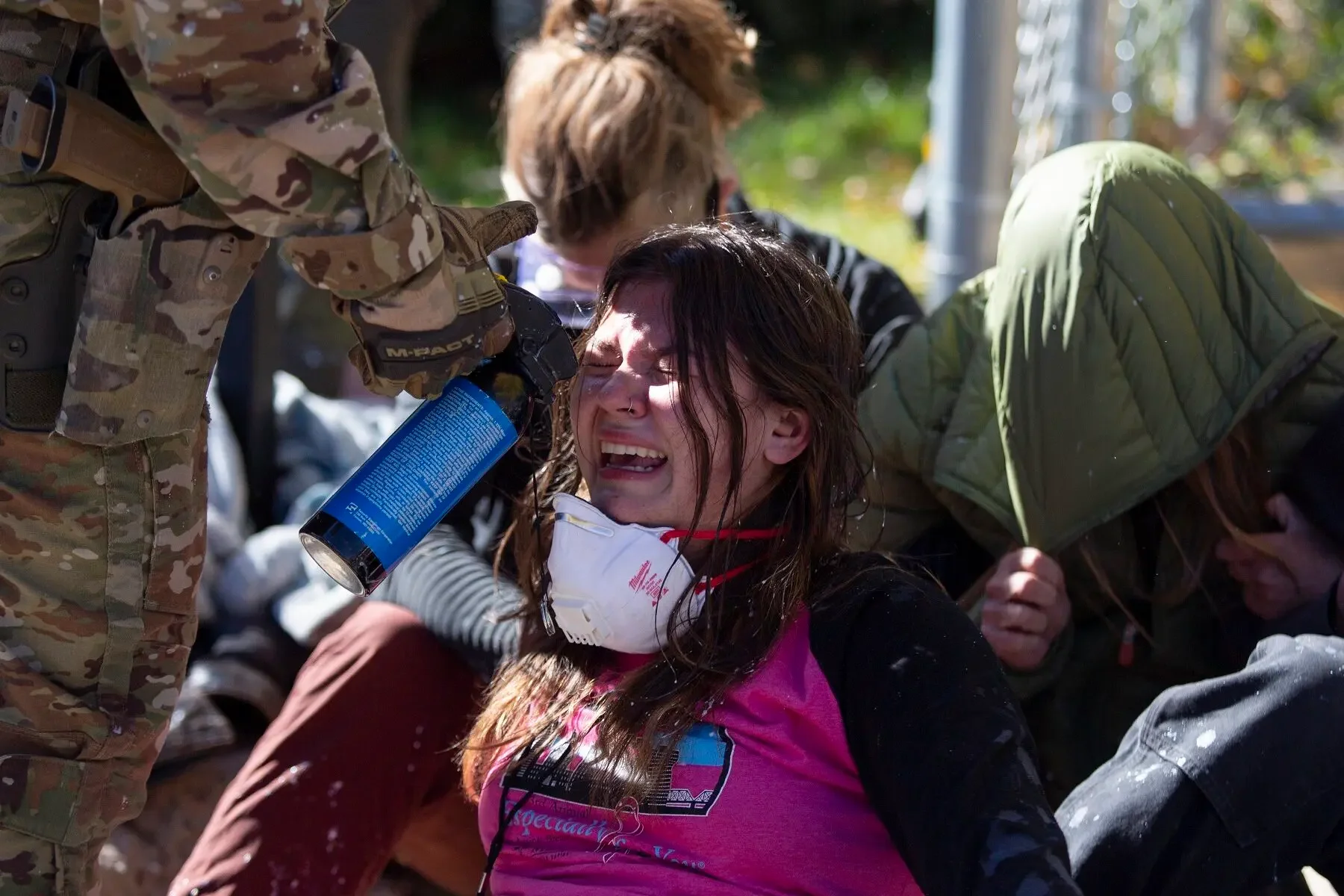 Peaceful protesters link arms while being pepper sprayed with MACE  in October 2025 in Durango, Colorado.