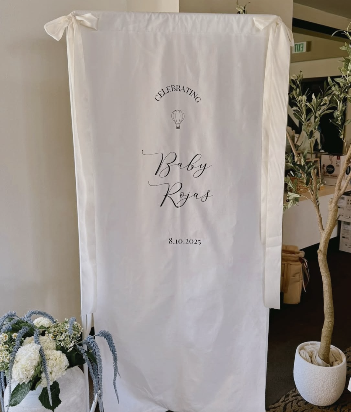 Celebrating Baby Rojas with a white fabric backdrop and floral arrangement.