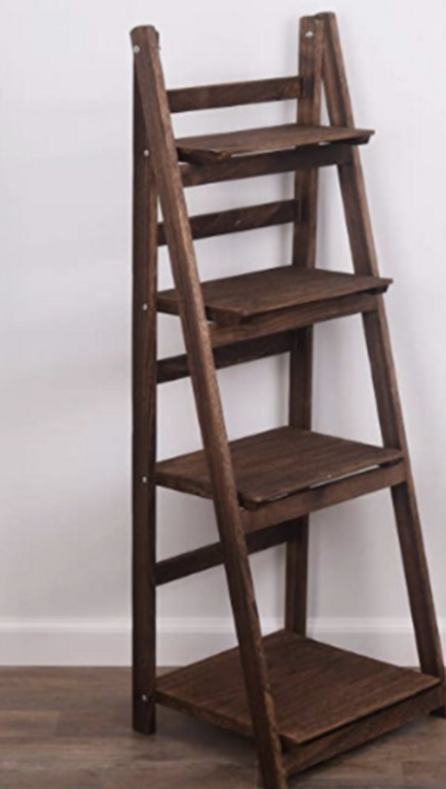 A wooden ladder shelf with four tiers, leaning against a white wall.