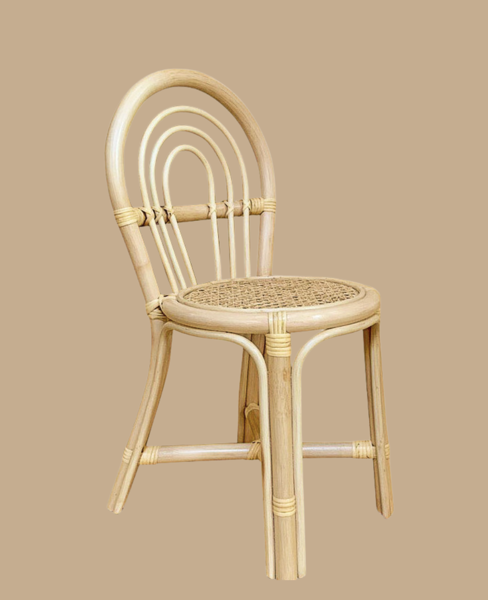 A light-colored rattan chair with a woven cane seat and a curved backrest against a beige background.