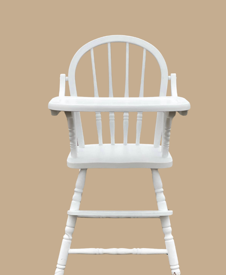 White wooden high chair on a beige background.