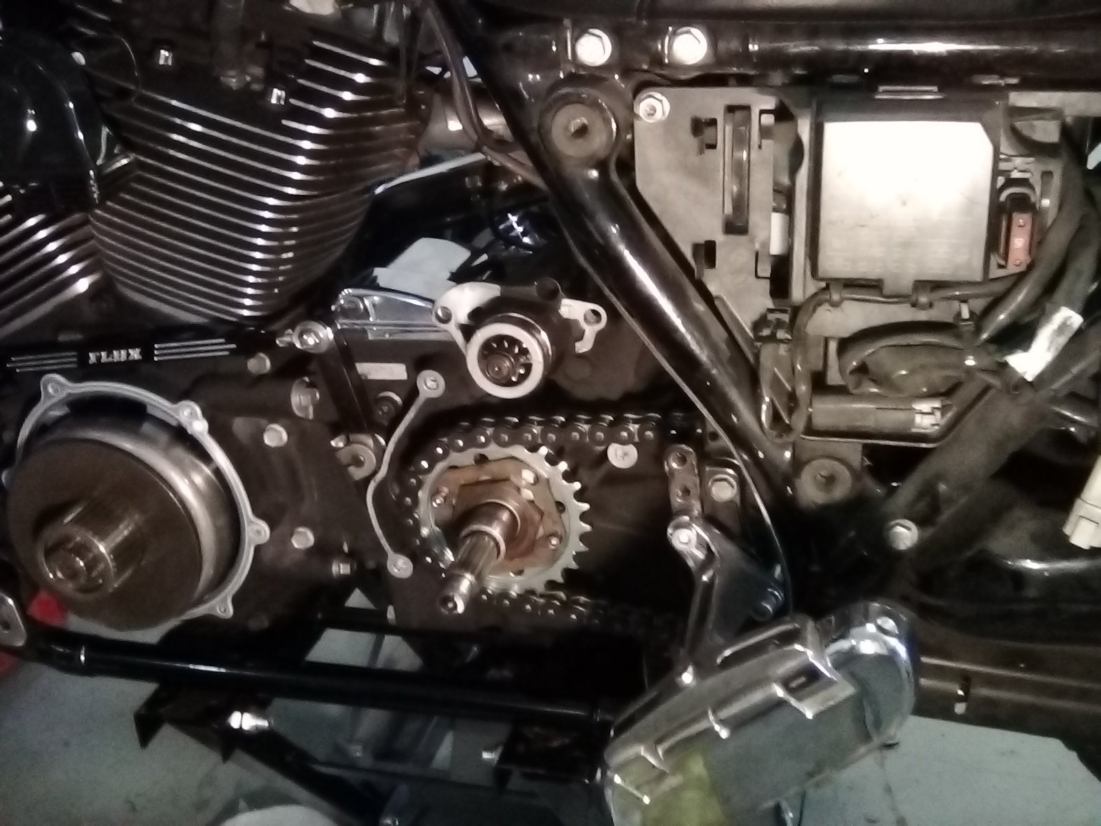 Close-up of a motorcycle engine with visible chain drive and various mechanical components.