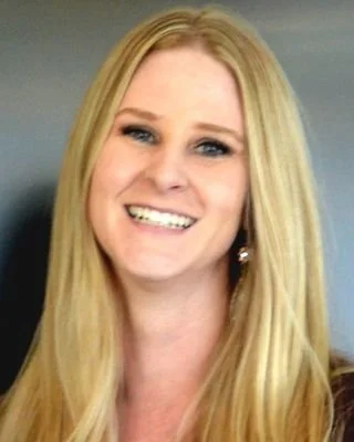 A woman with long blonde hair smiling at the camera.