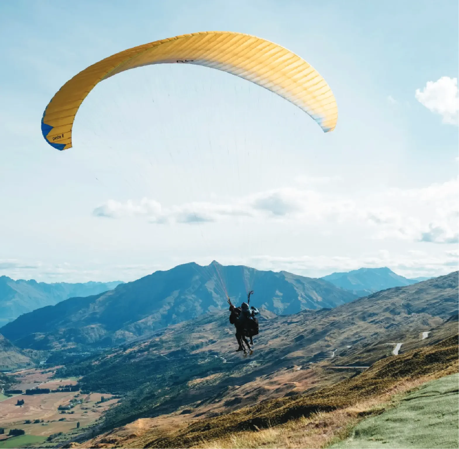 A person paragliding over a mountainous landscape during the day.