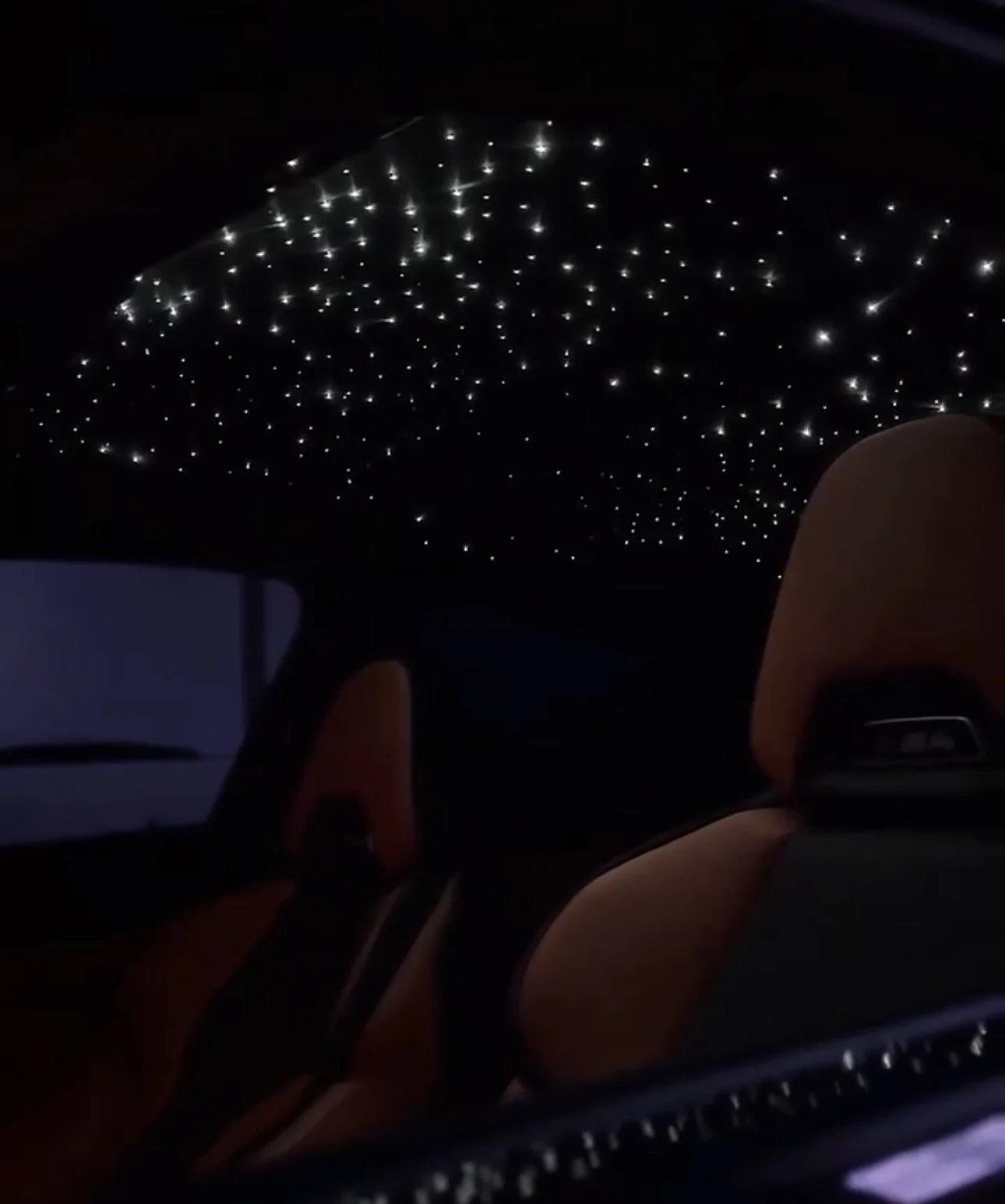 Interior of a car at night with a ceiling decorated with small LED star lights.
