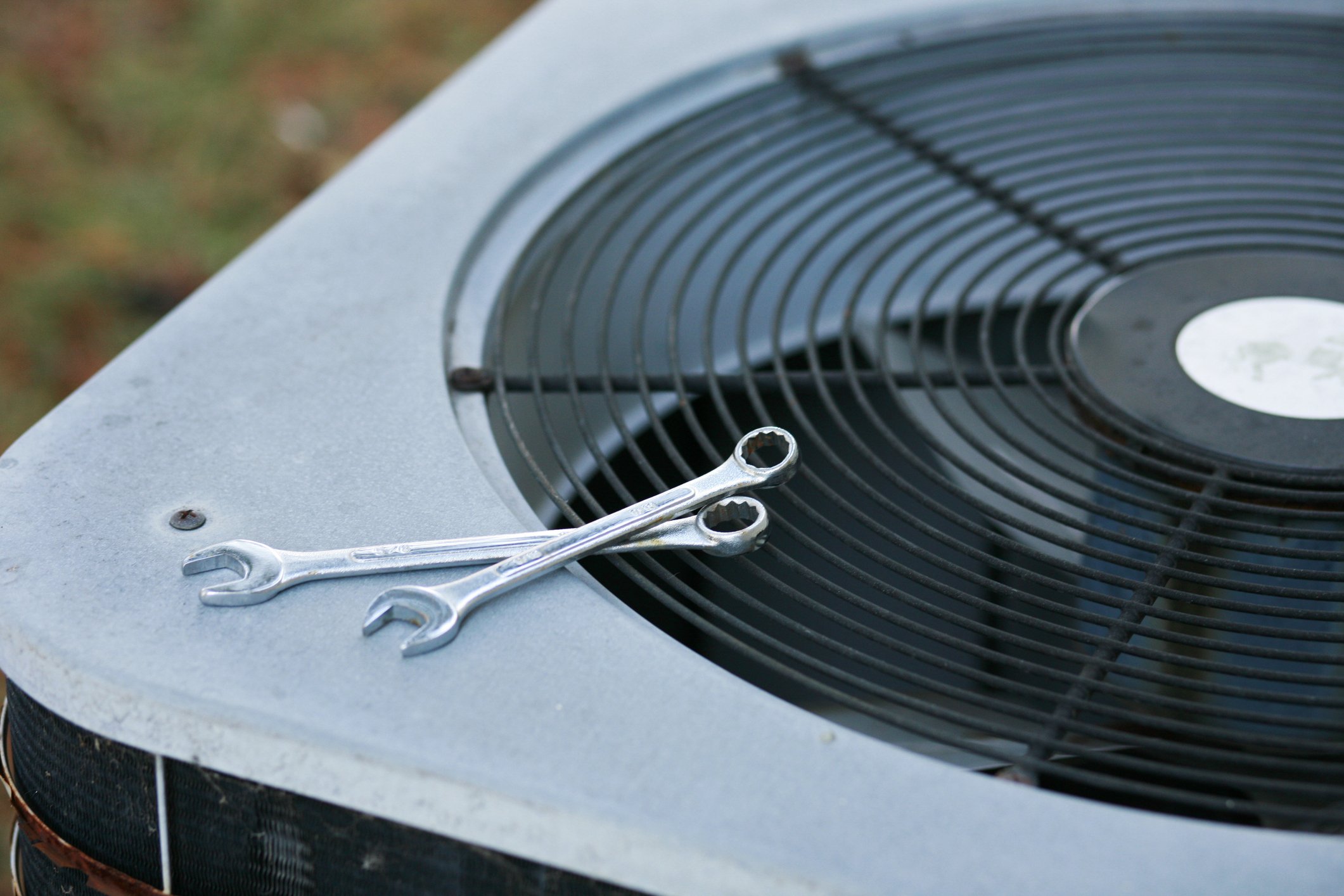 Two wrenches resting on an outdoor air conditioning unit