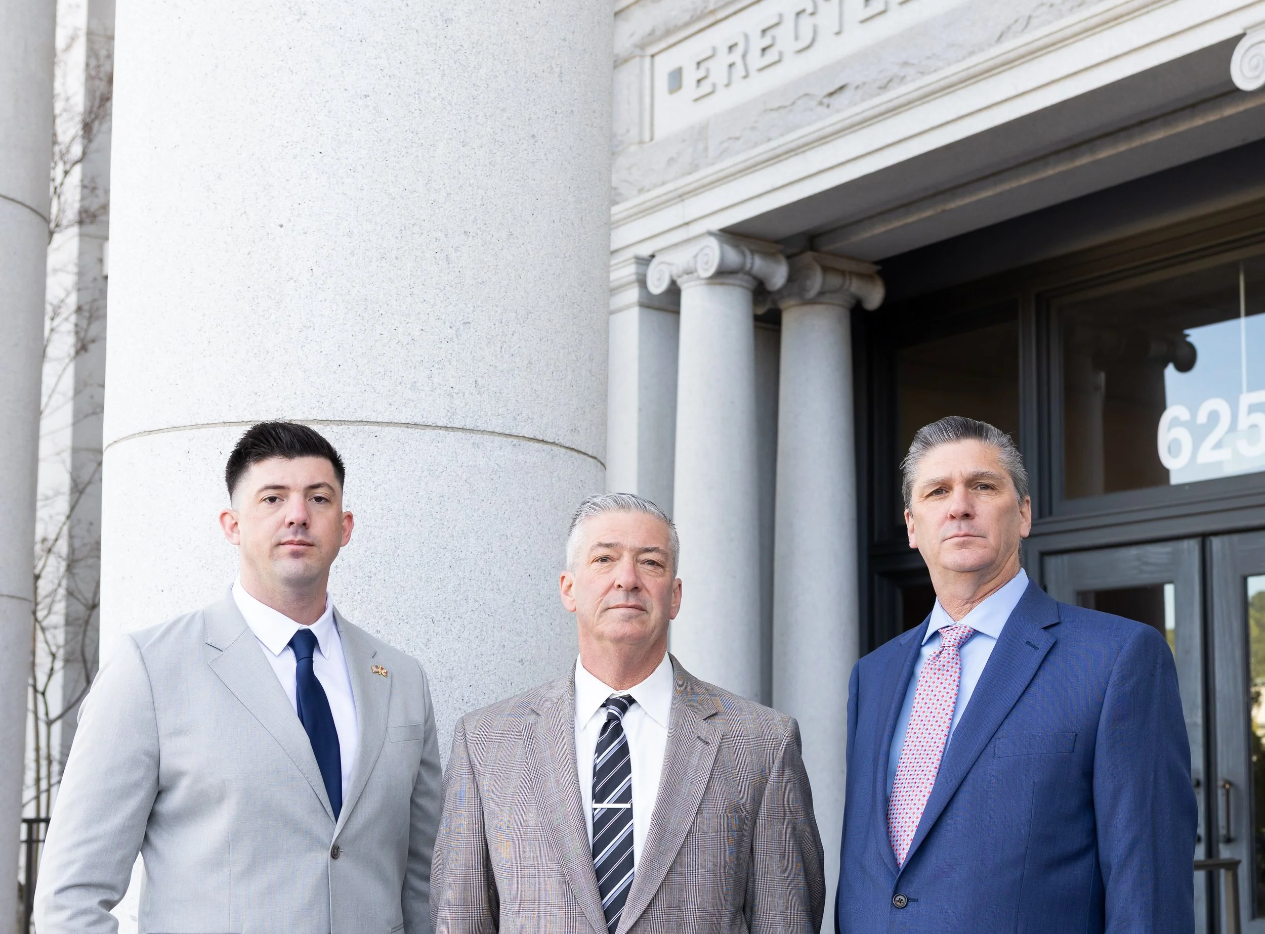 Three Northern California Eminent domain attorneys standing in front of courthouse columns, prepared to defend private property owner's rights in eminent domain litigation.