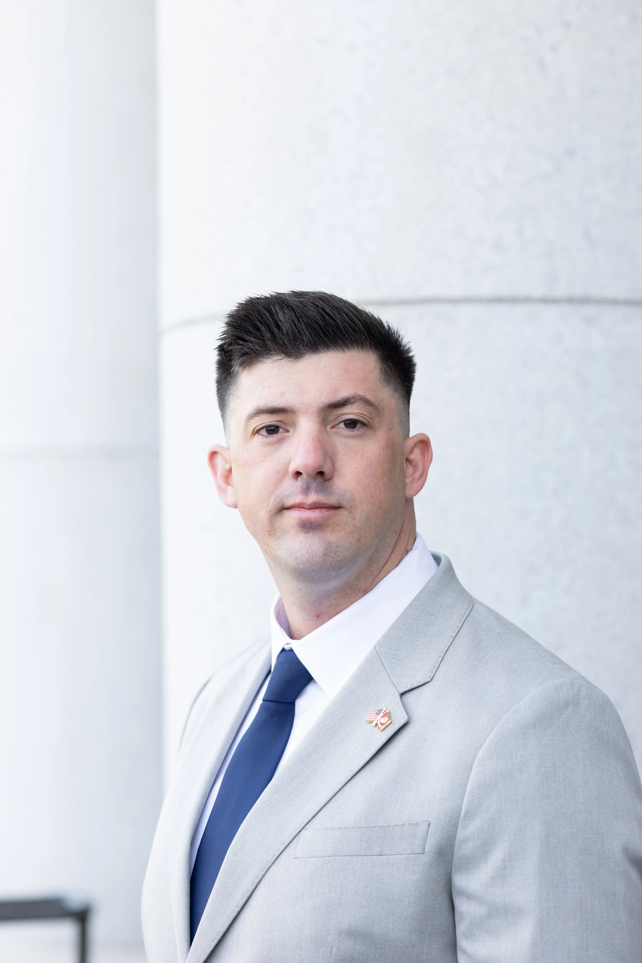 Northern California Eminent Domain Attorney in a gray suit, white shirt, and striped tie, standing in front of courthouse columns prepared to defend property owners' rights against condemnation lawsuits in California